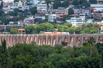 A long bridge with arches is seen in the distance. The bridge is surrounded by trees and buildings....