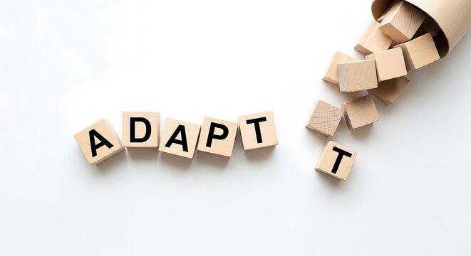 Wooden blocks spell adapt with cubes spilling from a paper container - Powered by Adobe