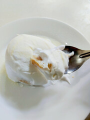 Spoon Scooping a Piece of Soft and Creamy Asian Milk Bun Dessert from a White Plate