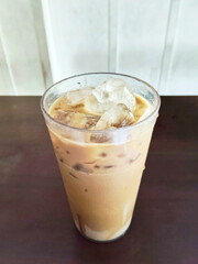 Refreshing Tall Glass of Iced Milk Tea or Teh Tarik with Ice Cubes on a Dark Table