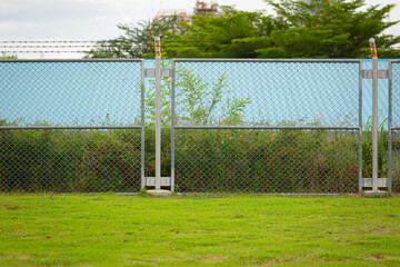 Fototapeta premium Steel mesh fence with a green lawn in the foreground, representing security, boundary, outdoor landscape,
