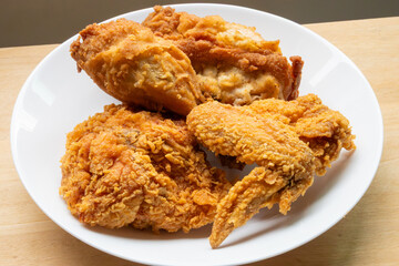Crispy fried chicken in white plate on wood table