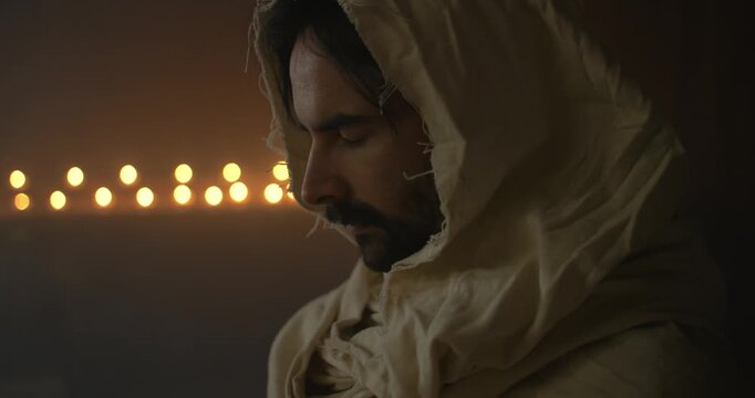 Closeup of Jesus Christ Praying with Closed Eyes in ambient light for Christianity stock footage.