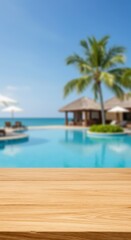 Blank wooden table against blur tropical resort background with pool and palm trees. Showcase for product display or advertisement on summer vacation theme for banner or poster with empty space.