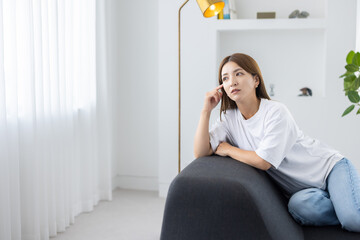 Woman sitting on sofa and relaxing in bright living room with natural light
