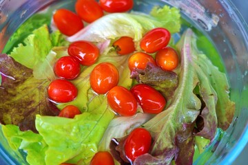 Fresh salad greens and cherry tomatoes soaking in water for cleaning and preparation