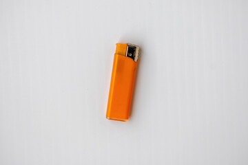 Bright orange plastic gas lighter with a metal nozzle, isolated on a white background. Top view close-up. Kitchen accessory for stoves, candles, and grills. Fire starter tool.