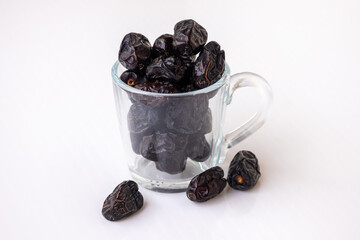 Delicious, healthy, and organic Ajwa dates, a premium Arabic fruit, neatly arranged in a clear glass cup. Nutritious energy food, perfect for Ramadan or Muslim holidays.