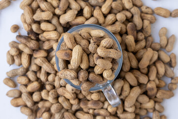 Heap of whole, unsalted peanuts in a transparent glass container. Top-down, close-up view. Natural, high-fiber, and delicious legume for a vegan and healthy diet.