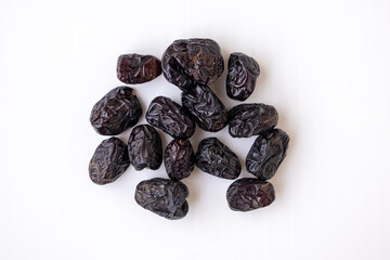 Ajwa dates fruit isolated on white background. Close-up of whole dried, dark brown, wrinkled dates. Natural, vegan, healthy Arabian dessert food for energy and nutrition.