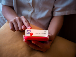 Close-up of hand holding red smartphone with suspicious new message notification, symbolizing SMS...