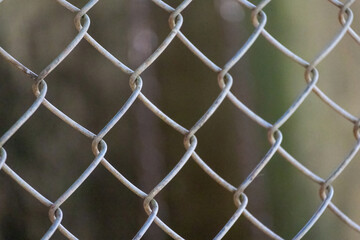 Detail of a worn, rusted metal mesh fence, chain-link pattern. Boundary or security barrier with...