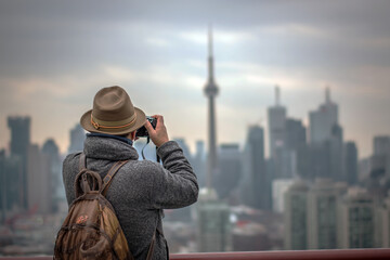 Fototapeta premium Traveler taking photo of modern city skyline on cloudy day