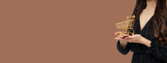 Woman with a mini shopping cart on brown backdrop