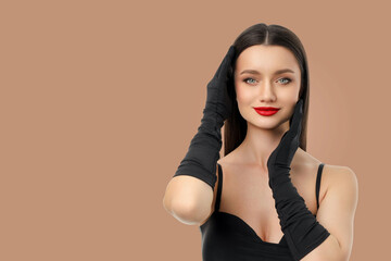 Obraz premium Woman in black gloves and red lipstick on beige background
