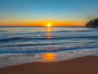 Obraz premium Ocean Sunrise Under Clear Skies with Orange Horizon