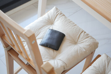 Black wallet resting on a cushioned chair. lost wallet concept 
