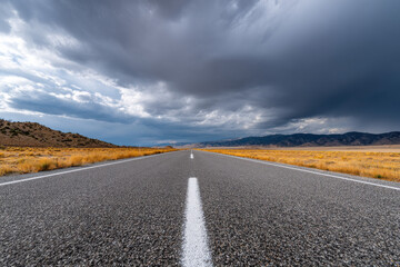 Fototapeta premium Empty highway stretching into the horizon under dramatic clouds