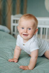 Portrait of a 8 month old crawling baby on the bed. the baby smiles and looks at the camera