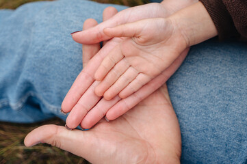 A close-up of a mother and father holding a child's hand. Concept of love, parenthood, and family