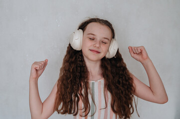 A carefree girl with headphones listens to music and dances