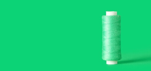 Spool of thread on green background with space for text