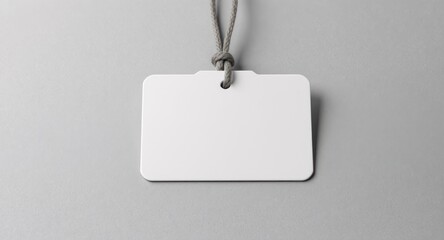 Plain white badge with gray string against neutral gray background, center view