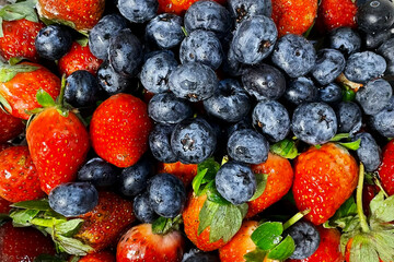 Close-up of assorted fresh blueberries and strawberries in mesh bowl, horizontal shot