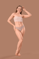 Naklejka premium Beautiful happy young woman in underwear on beige background