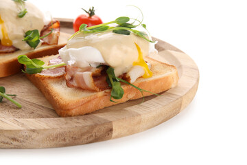 Wooden plate of delicious eggs Benedict with bacon and micro green on white background