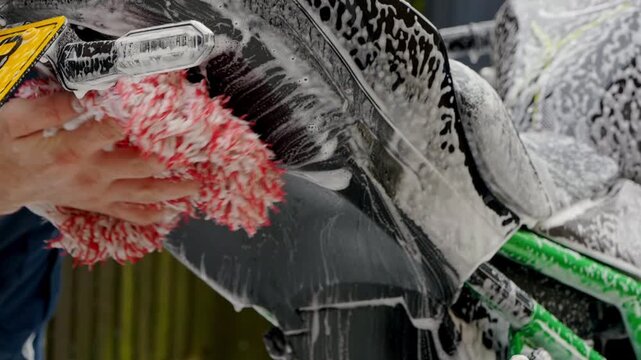 Cleaning rear of motorbike mud fender with snow foam shampoo