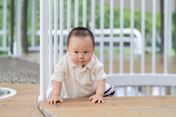 A young Asian boy practising crawling in an outdoor playground.