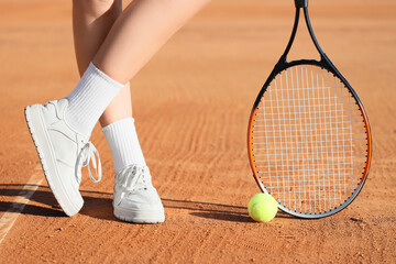 Sporty young woman with racket and tennis ball on court, closeup