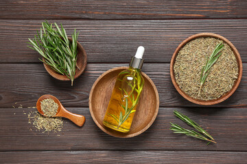 Bottle of rosemary cosmetic oil on wooden background