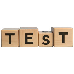 Wooden blocks spelling "TEST" in large, black capital letters, arranged horizontally against black