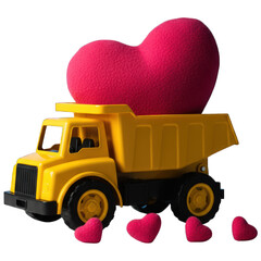 Yellow toy truck transports a large red heart, with smaller hearts scattered on the ground