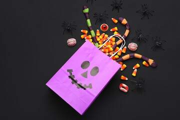 Composition with paper shopping bag and different jelly candies for Halloween on black background