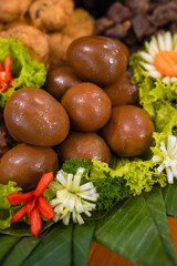 High-detail close-up of traditional marinated brown eggs (telur pindang) on a banana-leaf platter with lettuce and carved vegetable garnishes