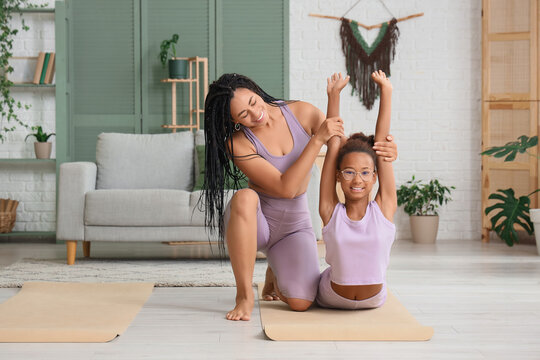African-American mother with her teenage daughter practicing yoga at home