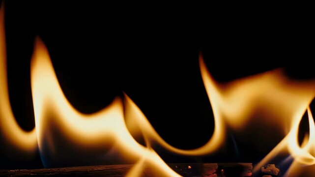 Close-up of flames dancing in the dark with warm hues of gold, orange, and yellow against black