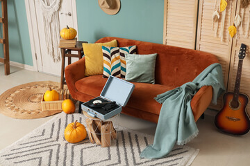 Interior of stylish living room with sofa, record player and pumpkins