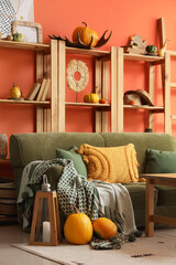 Interior of stylish living room with green sofa, shelf unit and pumpkins