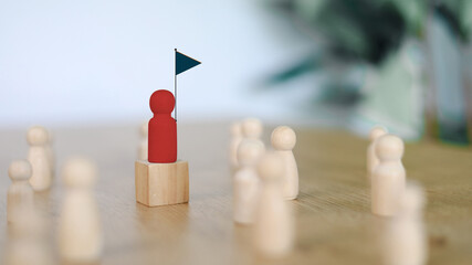 Leadership and individuality concept. Red wooden figure standing on block surrounded by natural wooden figures representing leader, uniqueness, and teamwork.