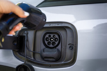 Gray electric car with EV charging cable close up
