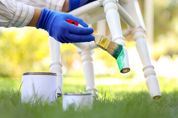 Female hands painting white stool in garden, closeup