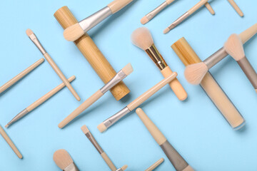 Composition with different makeup brushes, mascara and concealer on blue background, closeup