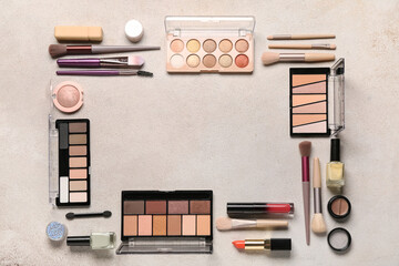 Frame made of makeup brushes and cosmetic products on beige grunge background