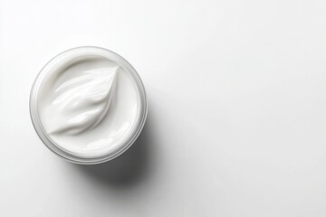 Top view of a white cosmetic cream in a round jar on a plain white background, clean skincare concept.