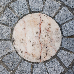Motif circulaire en pavés de pierre grise et centre en marbre clair