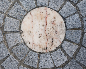 Motif circulaire en pavés de pierre grise et centre en marbre clair